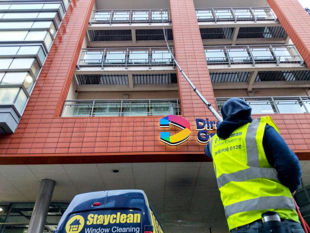 Stayclean cleaner using a long water-fed pole on a commercial building